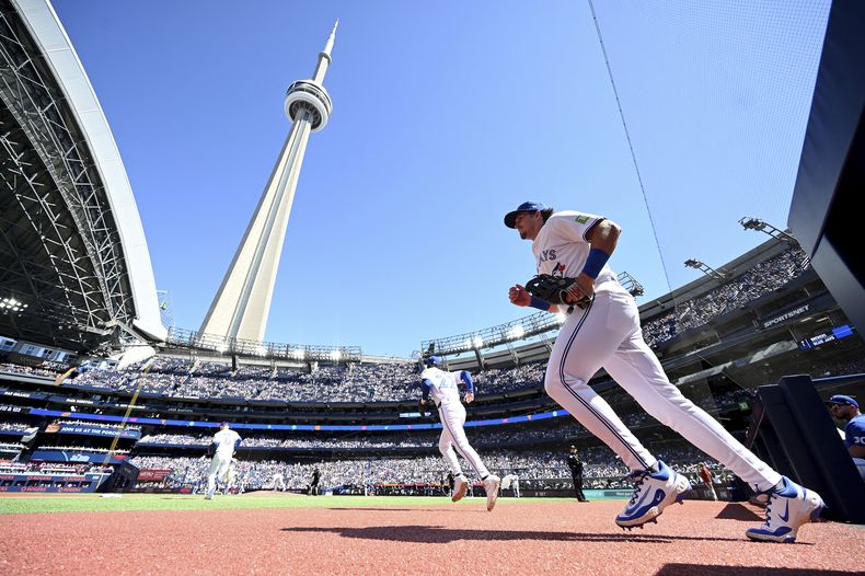 Addison Barger, a la derecha, y Ernie Clement, de los Azulejos de Toronto, salen al campo antes del inicio de un juego de béisbol contra los Cerveceros de Milwaukee en Toronto el domingo 31 de agosto de 2025. (Jon Blacker/The Canadian Press vía AP)