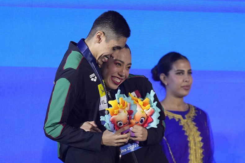 Los medallistas de bronce mexicanos Miranda Barrera y Diego Villalobos celebran en el podio tras ganar la medalla de bronce la prueba de dueto técnico mixto de la natación artística en el Mundial de Natación en Doha, Qatar, el domingo 4 de febrero de 2024. (AP Foto/Lee Jin-man)