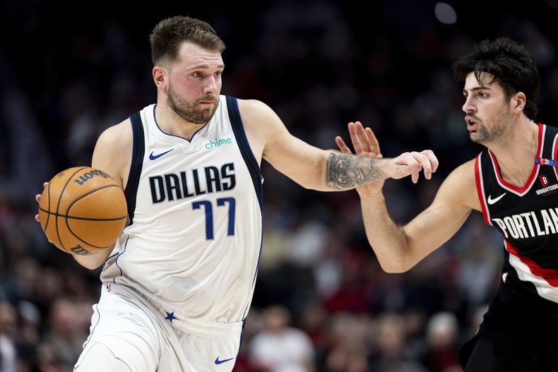 Luka Doncic, izquierda, de los Mavericks de Dallas, conduce el balón frente a Deni Avdija, derecha, de los Trail Blazers de Portland, durante la primera mitad del juego de baloncesto de la NBA, el domingo 1 de diciembre de 2024, en Portland, Oregon. (AP Foto/Howard Lao)