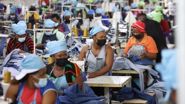 ARCHIVO - Matumelo Manosa, centro, trabaja en una fábrica textil en Maseru, Lesoto, el jueves 24 de febrero de 2022. (AP Foto/Neo Ntsoma, Archivo)