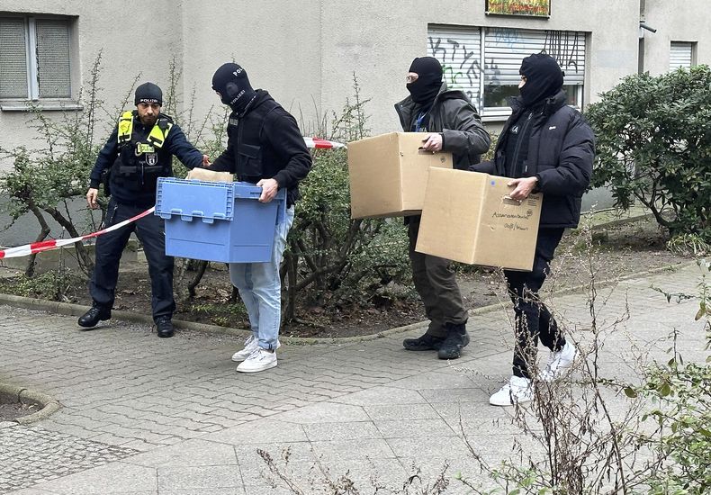 Investigadores ingresan con recipientes y cajas de cartón en la casa de la exterrorista de la Facción Ejército Rojo Daniela Klette en Berlín, el miércoles 28 de febrero de 2024. (Paul Zinken/dpa vía AP)
