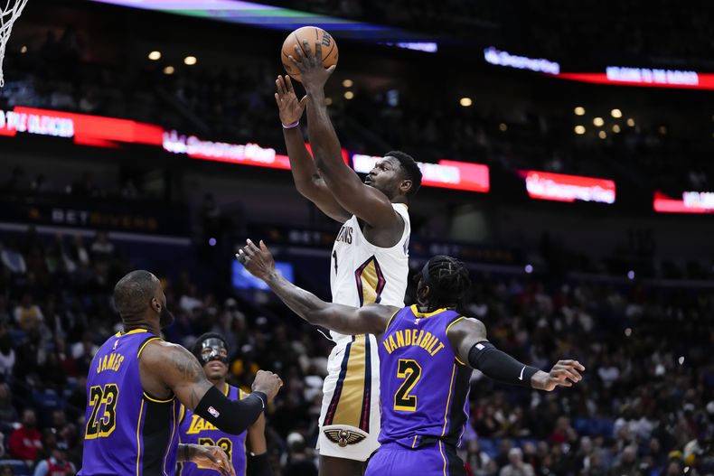 El alero de los Pelicans de Nueva Orleans Zion Williamson (1) va hacia el aro sobre el alero de los Lakers de Los Ángeles LeBron James (23) y Jarred Vanderbilt (2) en la primera mitad del juego de baloncesto de la NBA en Nueva Orleans, el domingo 31 de diciembre de 2023. (AP Foto/Gerald Herbert)