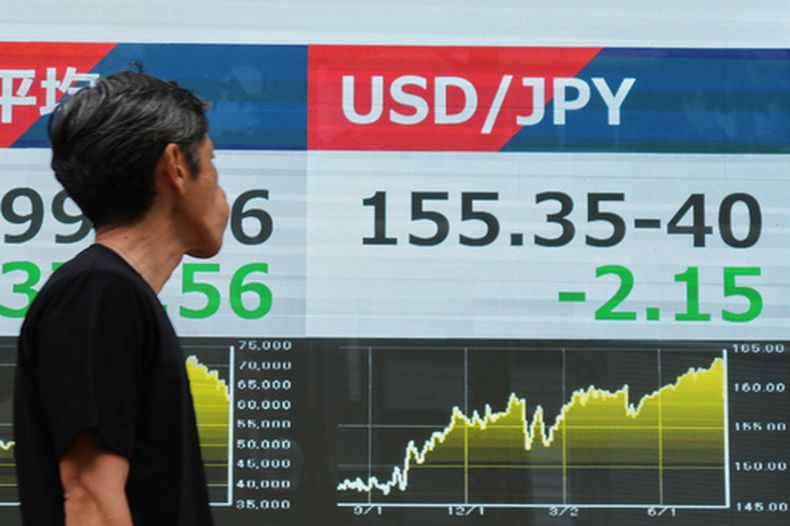 Un hombre pasa junto a un panel electrónico que muestra el tipo de cambio entre el dólar estadounidense y el yen japonés en una empresa de valores, el lunes 3 de agosto de 2026, en Tokio. (AP Foto/Eugene Hoshiko)