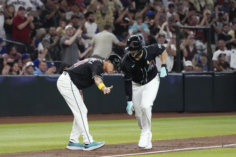 Randal Grichuk de los Diamondbacks de Arizona celebra con el entrenador de tercera base Tony Perezchica su jonrón de tres carreras ante los Dodgers de Los Ángeles el domingo primero de septiembre del 2024. (AP Foto/Ross D. Franklin)