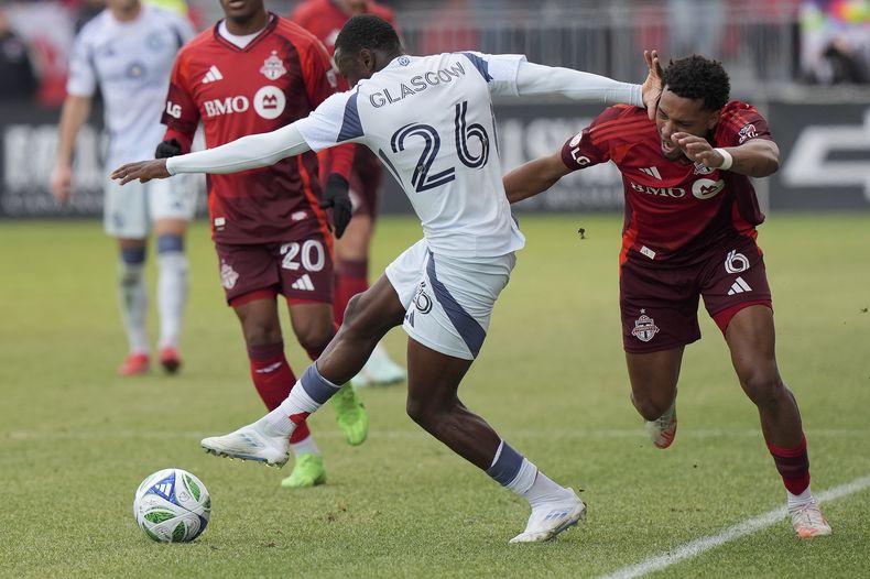 El mediocampista del Toronto FC Kosi Thompson (6) intenta detener al delantero del Chicago Fire, Omari Glasgow (26), mientras recibe un disparo durante la segunda mitad de un partido de fútbol de la MLS en Toronto, el sábado 15 de marzo de 2025. (Frank Gunn/The Canadian Press vía AP)