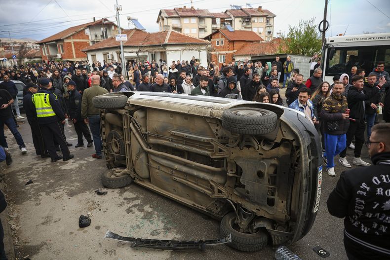 La multitud vuelca un vehículo en una protesta cerca de la vivienda del propietario del club nocturno en que se registró un incendio mortal, después de una vigilia por las víctimas de la tragedia, en el poblado de Kocani, en Macedonia del Norte, el lunes 17 de marzo de 2025. (AP Foto/Armin Durgut)