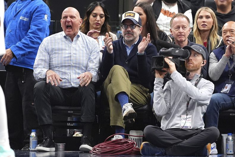El propietario de los Clippers de Los Angeles, Steve Ballmer, a la izquierda, y el actor Jason Sudeikis celebran después de que los Clippers anotaran durante la segunda mitad de un partido de baloncesto de la NBA contra los Grizzlies de Memphis, el miércoles 12 de febrero de 2025, en Inglewood, California. (Foto AP/Mark J. Terrill)