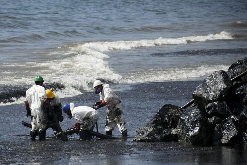 Trabajadores de la empresa de petróleo y gas Heritage limpian un derrame petrolero en la playa Rockly Bay, en Scarborough, en el sudoeste de Tobago, en Trinidad y Tobago, el 11 de febrero de 2024. (Foto AP/Akash Boodan)