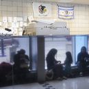 ARCHIVO - Migrantes procedentes de Venezuela se ven reflejados en una pared de mármol mientras encuentran refugio en la comisaría del distrito 16 del Departamento de Policía de Chicago el 1 de mayo de 2023. (AP foto/Charles Rex Arbogast, archivo)