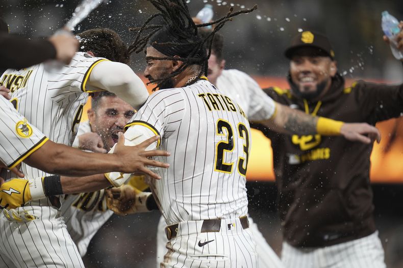 Fernando Tatis Jr., centro, de los Padres de San Diego, celebra con sus compañeros después de batear un elevado de sacrificio decisivo durante la décima entrada del juego de béisbol de Grandes Ligas contra los Rojos de Cincinnati, el lunes 8 de septiembre de 2025, en San Diego. Jake Cronenworth anotó la carrera del triunfo desde tercera base en la jugada. (AP Foto/Gregory Bull)