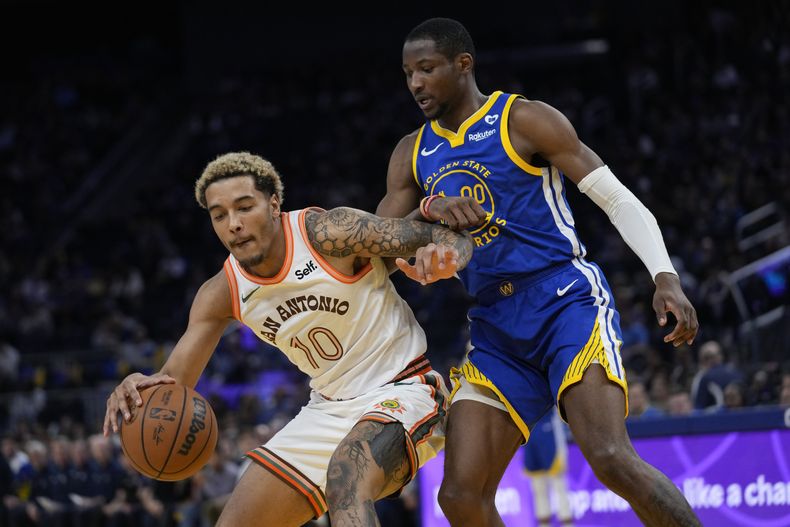 Jeremy Sochan, alero de los Spurs de San Antonio, trata de eludir a Jonathan Kuminga, de los Warriors de Golden STate, el sábado 9 de marzo de 2024 (AP Foto/Godofredo A. Vásquez)