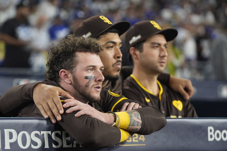 Jackson Merrill (izquierda), jardinero de los Padres de San Diego, mira junto con el relevista Jeremiah Estrada (centro) y el cátcher Kyle Higashioka el duelo en que su equipo fue eliminado por los Dodgers de Los Ángeles, el viernes 11 de octubre de 2024 (AP Foto/Mark J. Terrill)
