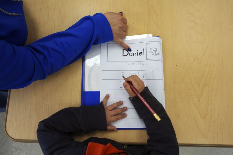 ARCHIVO - Tania Ortiz, profesora auxiliar del programa Head Start de Easterseals, ayuda a un alumno a practicar el escribir su nombre, el 29 de enero de 2025, en Miami. (AP Foto/Rebecca Blackwell, archivo)