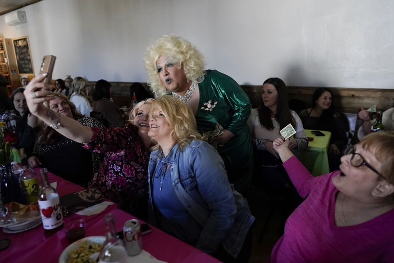 La drag queen Alexus Daniels, vestida como Dolly Parton, posa para selfies con miembros de la audiencia mientras actúa en Spring Fever Drag Brunch, el domingo 26 de marzo de 2023, en Kulpmont Winery en Kulpmont, Pensilvania. (Foto AP/Carolyn Kaster)