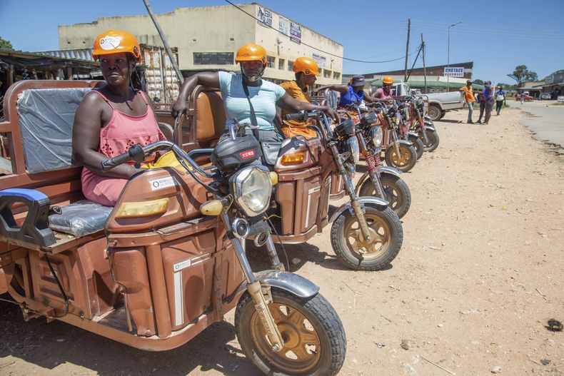 Mujeres en sus triciclos eléctricos aguardan la llegada de clientes en un mercado, el jueves 6 de marzo de 2025, en Hwedza, Zimbabue. (AP Foto/Aaron Ufumeli)