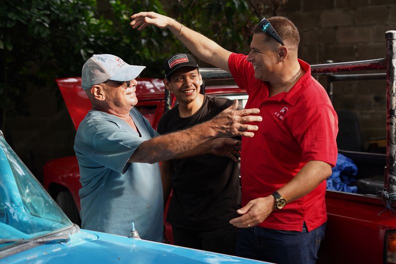 El periodista salvadoreño Mario Guevara (derecha) saluda a sus vecinos tras llegar a la casa de un familiar en Apopa, El Salvador, tras su deportación de Estados Unidos, el viernes 3 de octubre de 2025. (Foto AP/Salvador Meléndez)