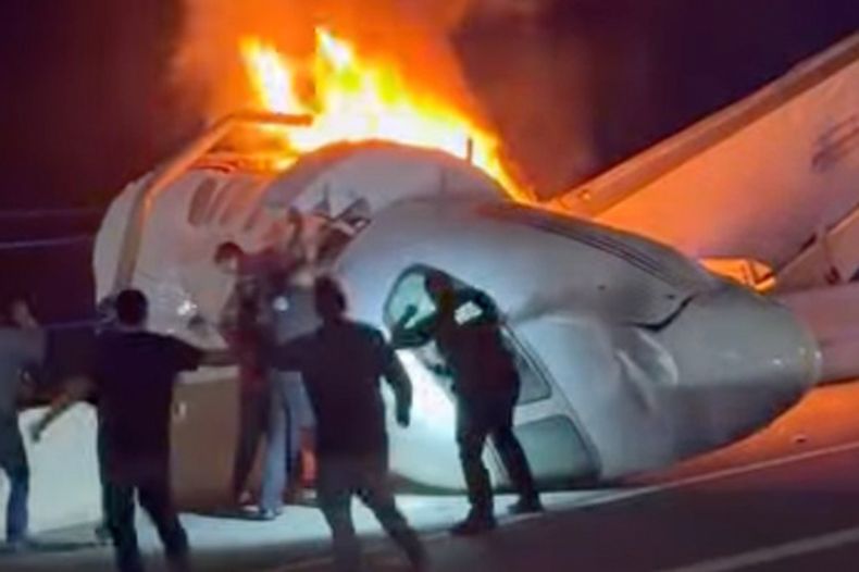 Un pasajero, en la parte superior de la imagen, salta de un avión que se estrelló en una autopista, mientras otras personas ayudan, el martes 16 de junio de 2026, en Laredo, Texas. (Zayra Garza vía AP)