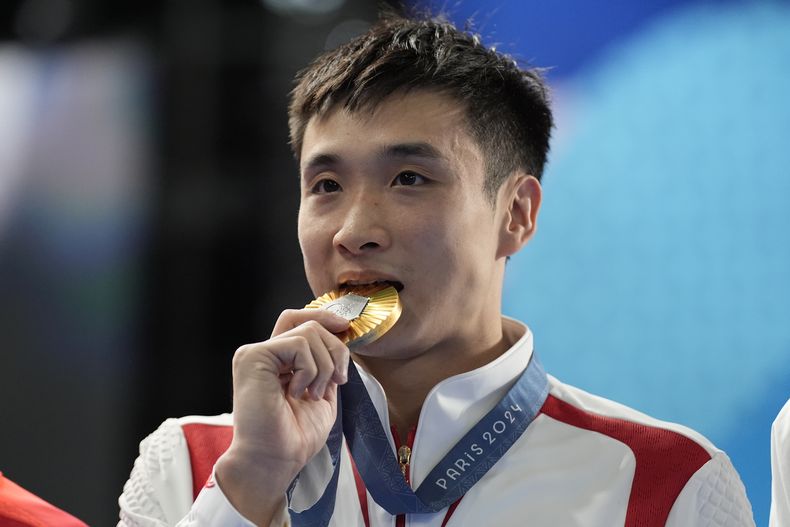 El chino Cao Yuan, muerde la medalla de oro tras la final de plataforma de 10 metros en los clavados olímpicos, el sábado 10 de agosto de 2024 en Saint-Denis, Francia (AP Foto/Lee Jin-man)