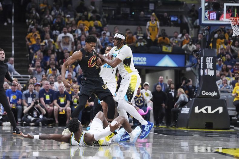 El escolta de los Pacers de Indiana, Bennedict Mathurin (00), cae a la cancha mientras el pívot Myles Turner empuja al alero de los Cavaliers de Cleveland, DeAndre Hunter (12), en la primera mitad del Juego 4 de las semifinales de la Conferencia Este de los playoffs de baloncesto de la NBA en Indianápolis, el domingo 11 de mayo de 2025. (AP Foto/Michael Conroy)