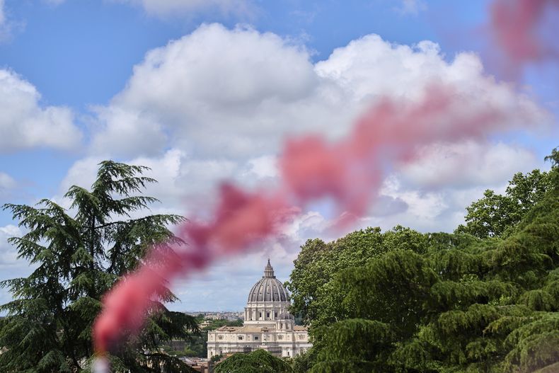 ARCHIVO - Humo rosa se alza ante la basílica de San Pedro durante una protesta de la Conferencia de Ordenación de Mujeres, que pide igualdad plena para las mujeres en la Iglesia católica, el primer día de su cónclave para elegir al 267mo papa en Roma, el miércoles 7 de mayo de 2025. (AP Foto/Bernat Armangue, Archivo)