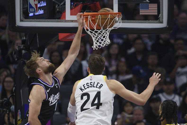 Domantas Sabonis, izquierda, de los Kings de Sacramento, clava el balón superando a Walker Kessler (24), del Jazz de utah, durante la primera mitad del juego de baloncesto de la NBA, el domingo 31 de marzo de 2024, en Sacramento, California. (AP Foto/Randall Benton)