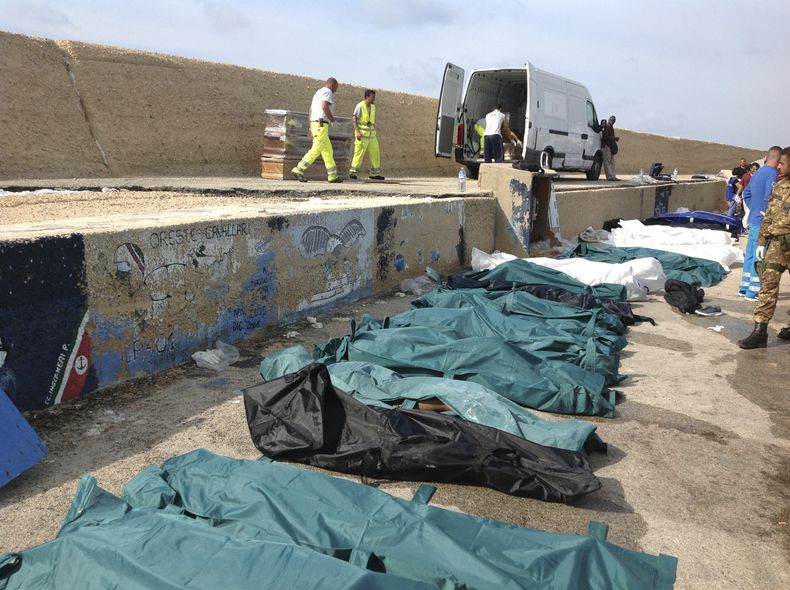 Los cad&aacute;veres de decenas de inmigrantes que murieron ahogados en un naufragio frente a la costa de Sicilia, son colocados en hilera en el puerto de Lampedusa el jueves 3 de octubre del 2013. Cerca de 100 personas murieron cuando un barco que llevab