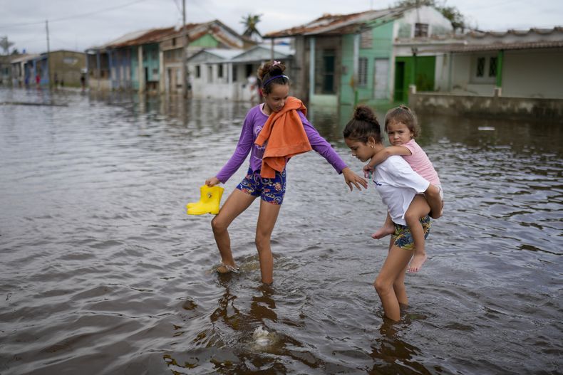 Unos niños caminan por una calle inundada tras el paso del huracán Rafael en Batabanó, Cuba, el jueves 7 de noviembre de 2024. (Foto AP/Ramón Espinosa)