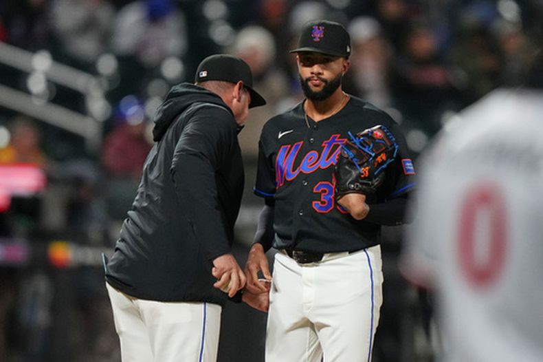El lanzador de los Mets de Nueva York, Devin Williams (derecha), le entrega la pelota al mánager Carlos Mendoza al salir durante la novena entrada de un partido de béisbol contra los Mellizos de Minnesota, el martes 21 de abril de 2026, en Nueva York. (AP Foto/Frank Franklin II)
