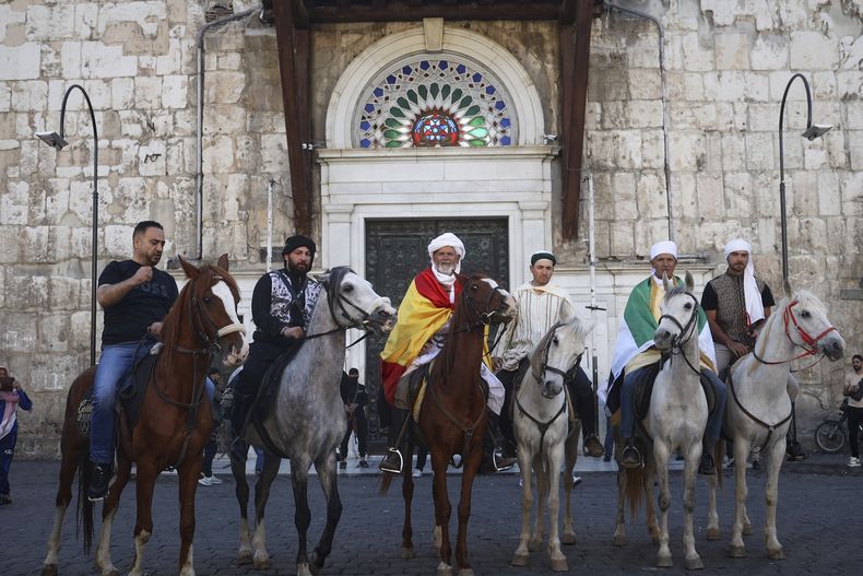 Varios peregrinos, incluidos tres de España, posan con sus caballos frente al mercado Souq al Hamidiyah durante su cabalgata de meses desde España a Arabia Saudí para participar en el Haj, el 21 de abril de 2025, en Damasco, Siria. (AP Foto/Omar Albam)