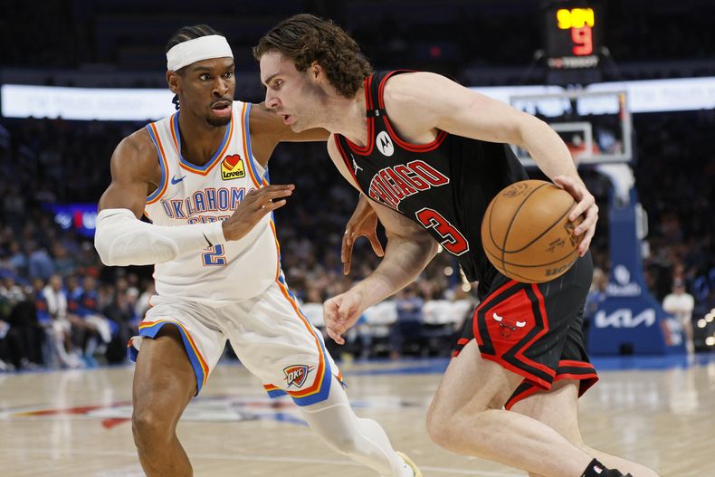 El base de los Bulls de Chicago Josh Giddey avanza hacia la canasta con el balón frente al base del Thunder de Oklahoma City Shai Gilgeous-Alexander el 31 de marzo del 2025. (AP Foto/Nate Billings)