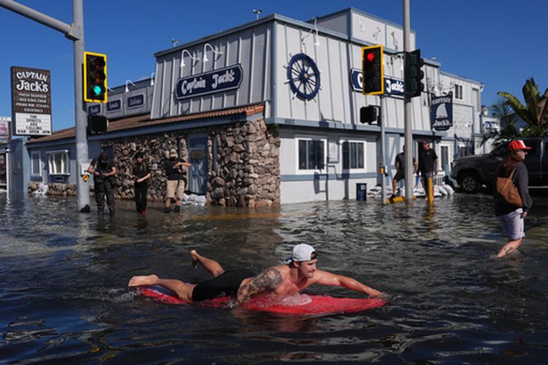 Un hombre surfea en una inundación, el miércoles 28 de octubre de 2026, en Huntington Beach, California. (AP Foto/Jae C. Hong)