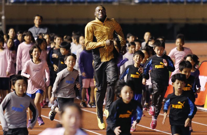 El velocista jamaiquino Usain bolt corre con ni&ntilde;os en una actividad el viernes, 22 de noviembre de 2013, en Tokio. (AP Photo/Shuji Kajiyama)
