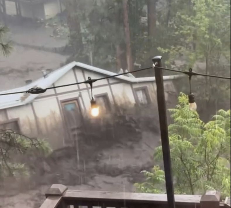 En esta imagen tomada de un video, una casa es arrastrada por una crecida tras una casa en Ruidoso, Nuevo México, el martes 8 de julio de 2025. (Kaitlyn Carpenter via AP)