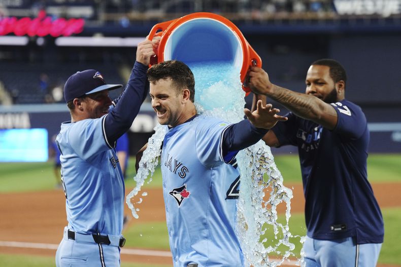 Ernie Clement, de los Azulejos de Toronto, es empapado por Myles Straw (izquierda) y Vladimir Guerrero Jr. tras el triunfo ante los Atléticos, el jueves 29 de mayo de 2025 (Nathan Denette/The Canadian Press via AP)