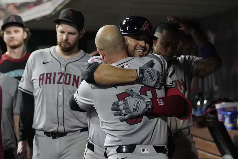 Eugenio Suárez, de los Diamondbacks de Arizona, abraza a Christian Walker (53) después de conectar un jonrón contra los Rojos de Cincinnati durante la octava entrada del juego de béisbol el miércoles 8 de mayo de 2024, en Cincinnati. (AP Foto/Carolyn Kaster)