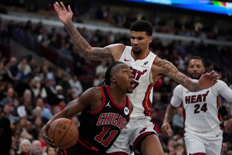Kelel Ware (7), derecha, del Heat de Miami, comete una falta a Ayo Dosunmu (11), de los Bulls de Chicago, durante la segunda mitad del juego de baloncesto de la Copa NBA, el viernes 21 de noviembre de 2025, en Chicago. (AP Foto/Erin Hooley)
