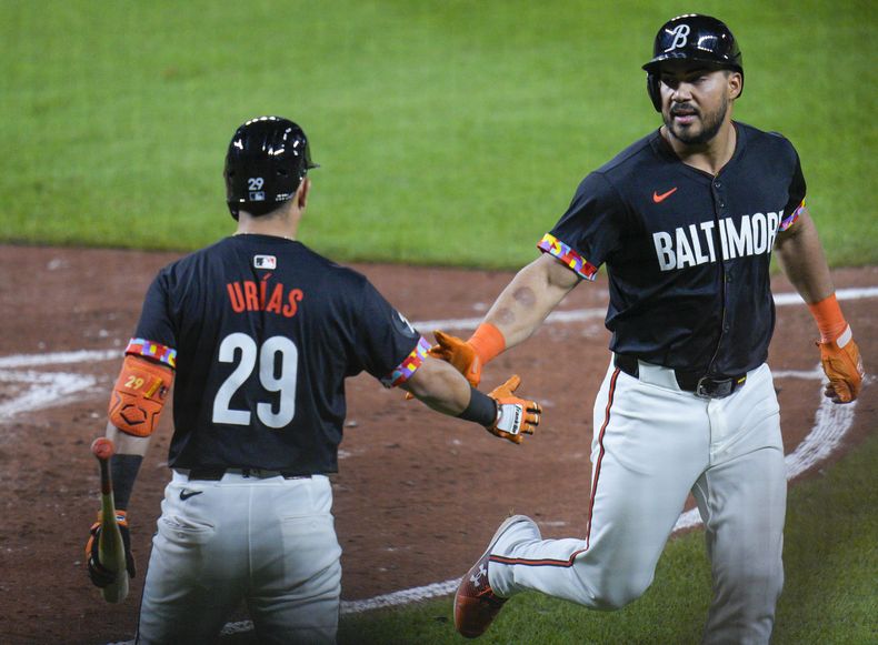 Anthony Santander, derecha, de los Orioles de Baltimore, choca manos con Ramón Urías (29) después de anotar carrera en contra de los Rays de Tampa Bay con imparable de Austin Hays durante la sexta entrada del juego de béisbol, el viernes 31 de mayo de 2024, en Baltimore. (AP Foto/Jess Rapfogel)