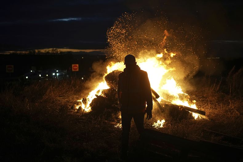 ARCHIVO - Un agricultor observa una fogata durante una protesta de agricultores contra el acuerdo comercial Unión Europea-Mercosur, el lunes 18 de noviembre de 2024, en Saint-Laurent-de-Mure, cerca de Lyon, en el centro de Francia. (AP Foto/Laurent Cipriani, archivo)