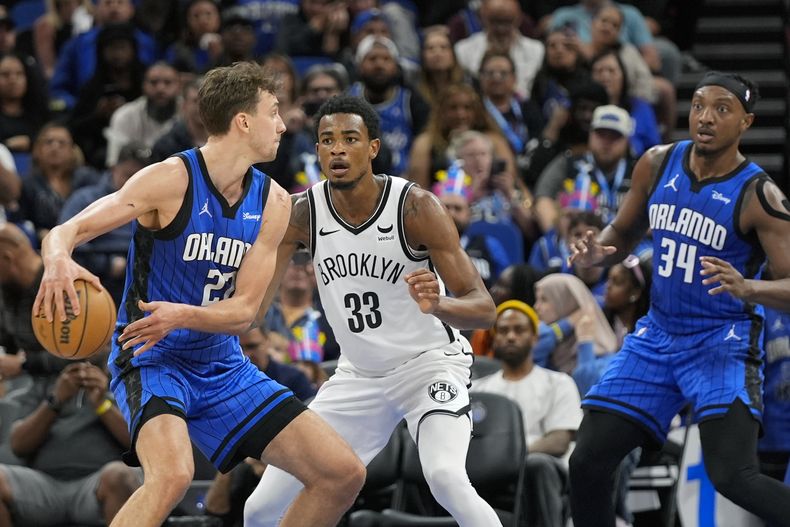 Frans Wagners, alero del Magic de Orlando, intenta enviar un pase frente a Nic Claxton, de los Nets de Brooklyn, en el partido del martes 27 de febrero de 2024 (AP Foto/John Raoux)