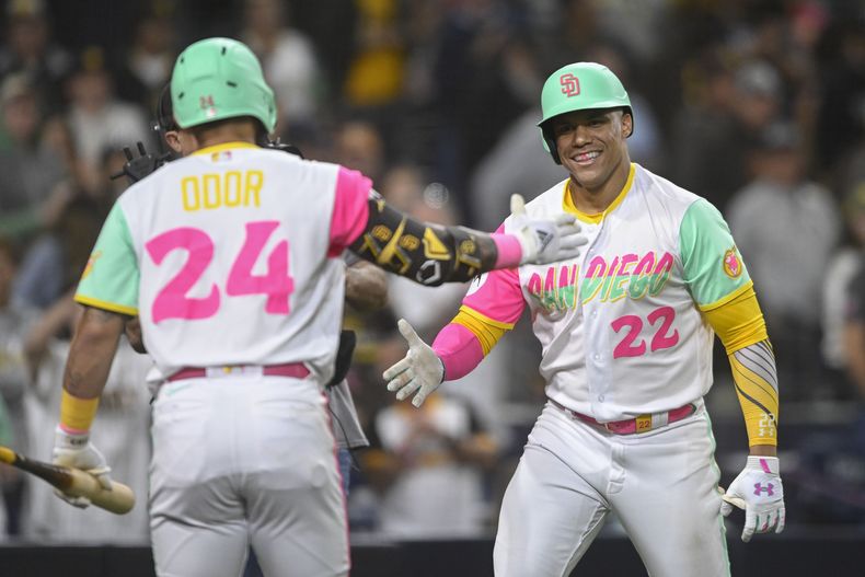 El dominicano Juan Soto, de los Padres de San Diego, es felicitado por su compañero venezolano Rougned Odor (24) después de que conectara un jonrón de dos carreras a los Nacionales de Washington en la octava entrada del partido en San Diego, el viernes 23 de junio de 2023. (AP Foto/Denis Poroy)