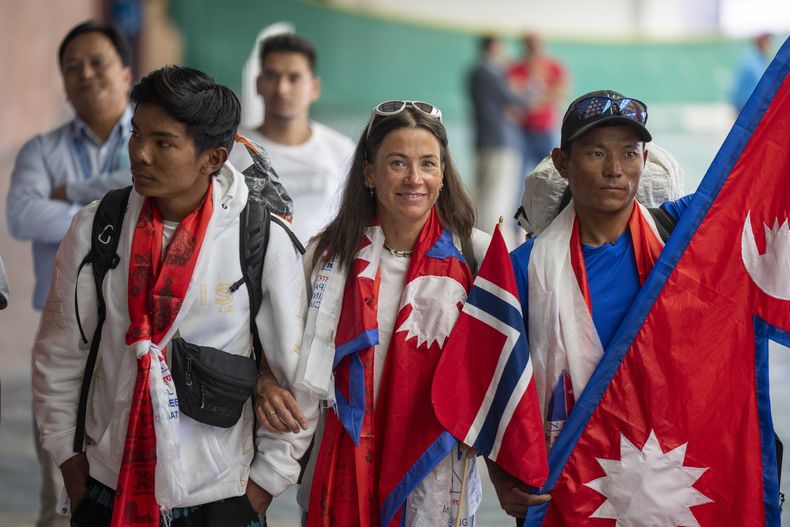 La escaladora noruega Kristin Harila (centro) y su sherpa Tenjen Sherpa (derecha), que el 3 de agosto establecieron un nuevo récord al subir las 14 cumbres más altas del mundo en 92 días, a su llegada al aeropuerto de Katmandú, Nepal, el 5 de agosto de 2023. (AP Foto/Niranjan Shreshta)