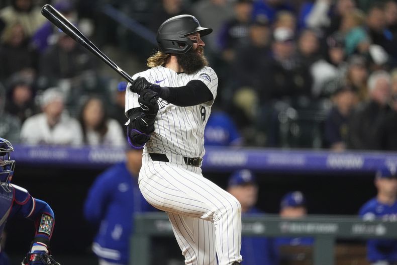 Charlie Blackmon, de los Rockies de Colorado, sigue el vuelo de la pelota de un doble que imphlsó dos carreras ante el relevista de los Rangers de Texas, Yerry Rodríguez, en la octava entrada del juego de béisbol el viernes 10 de mayo de 2024, en Denver. (AP Foto/David Zalubowski)