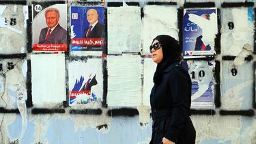 americateve | Una mujer pasa caminando junto a un muro empapelado con carteles electorales dos d&iacute;as antes de la primera vuelta de las elecciones presidenciales en T&uacute;nez, el 21 de noviembre de 2014. (Foto AP/Hassene Dridi)