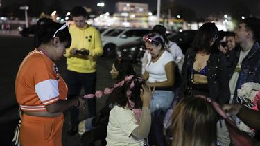 Una mujer se coloca extensiones de cabello rosadas previo al concierto de la gira Mañana será bonito de Karol G en el Estadio Azteca de la Ciudad de México el jueves 8 de febrero de 2024. (Foto AP/Eduardo Verdugo)