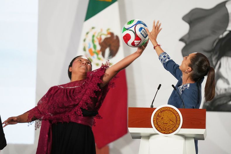 ARCHIVO - La presidenta mexicana Claudia Sheinbaum, a la derecha, y la futbolista amateur Yolett Cervantes intentan atrapar un balón durante la ceremonia de entrega de boletos para el partido inaugural del Mundial de la FIFA 2026, el 29 de mayo de 2026, en Ciudad de México. (AP Foto/Fernando Llano, archivo)