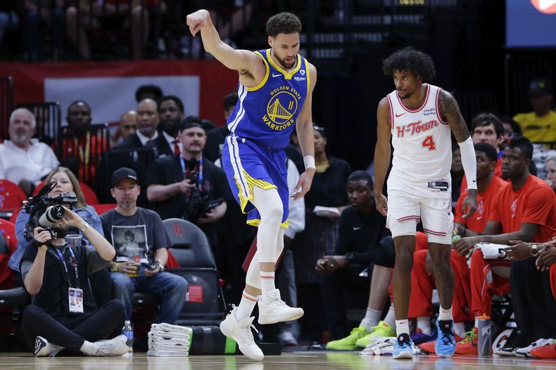 Klay Thompson, de los Warriors de Golden State, festeja su triple junto a Jalen Green, de los Rockets de Houston, en el partido del jueves 4 de abril de 2024 (AP foto/Michael Wyke)