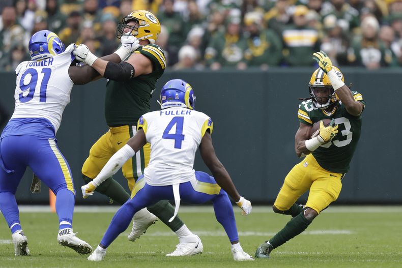 Aaron Jones (33), derecha, corredor de los Packers de Green Bay, acarrea el balón durante la primera mitad del juego de la NFL en contra de los Rams de Los Ángeles, el domingo 5 de noviembre de 2023, en Green Bay, Wisconsin. (AP Foto/Matt Ludtke)