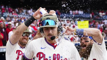 Kody Clemens y Brandon Marsh de los Filis lanza agua sobre Bryson Stott tras el triunfo después de que Stott conectó un jonrón en la séptima entrada en el juego ante los Cachorros de Chicago el domingo 21 de mayo del 2023. (AP Foto/Matt Rourke)