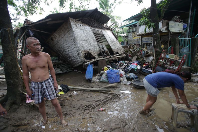 Vecinos frente a sus viviendas da&ntilde;adas horas despu&eacute;s que el tif&oacute;n Nari golpe&oacute; el poblado de San Miguel, en la provincia de Bulacan, en el norte de Filipinas, el domingo 13 de octubre de 2013. (Foto AP/Aaron Favila)