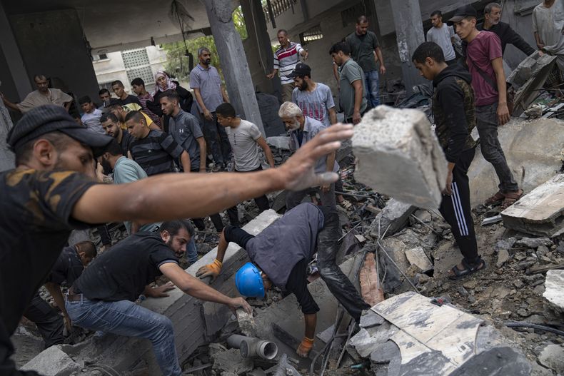 Palestinos buscan sobrevivientes en un edificio destruido por el bombardeo israelí en el campo de refugiados de Rafah, en la Franja de Gaza, el martes 17 de octubre de 2023. (AP Foto/Fatima Shbair)